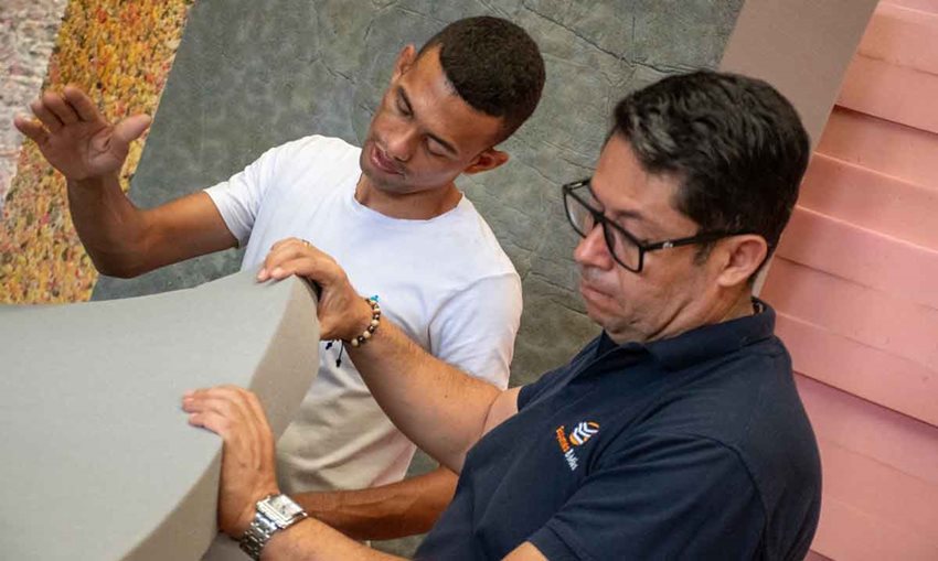 Dos hombres manipulando una espuma gris con las manos.