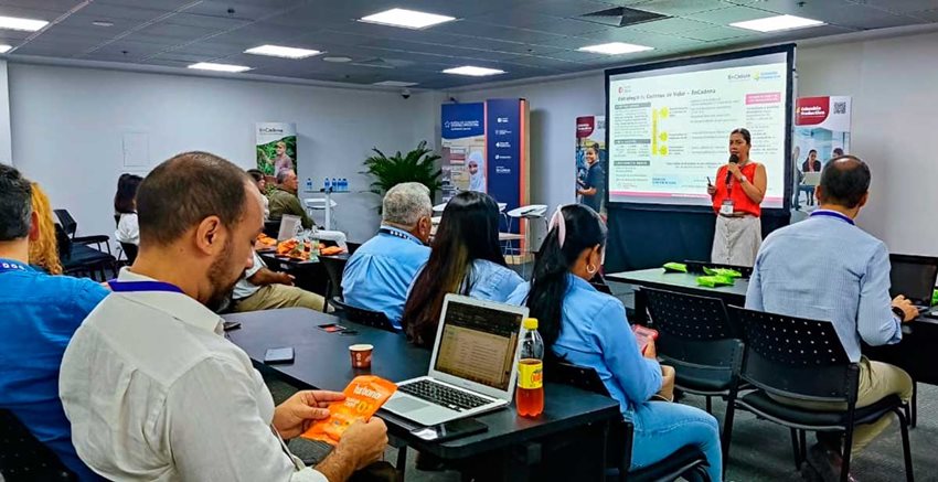 Mujer hablando por micrófono a personas, en medio de una conferencia.