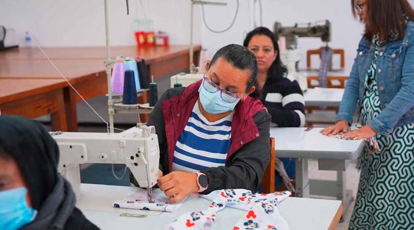 Mujeres frente a máquinas de coser, arreglando prendas.