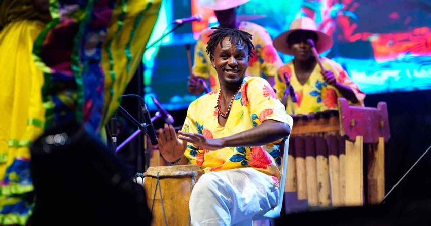 Hombres morenos con trajes típicos colombianos, tocando instrumentos autóctonos del país.