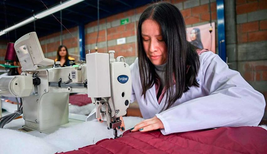 Una mujer cose unas telas en una máquina de coser.