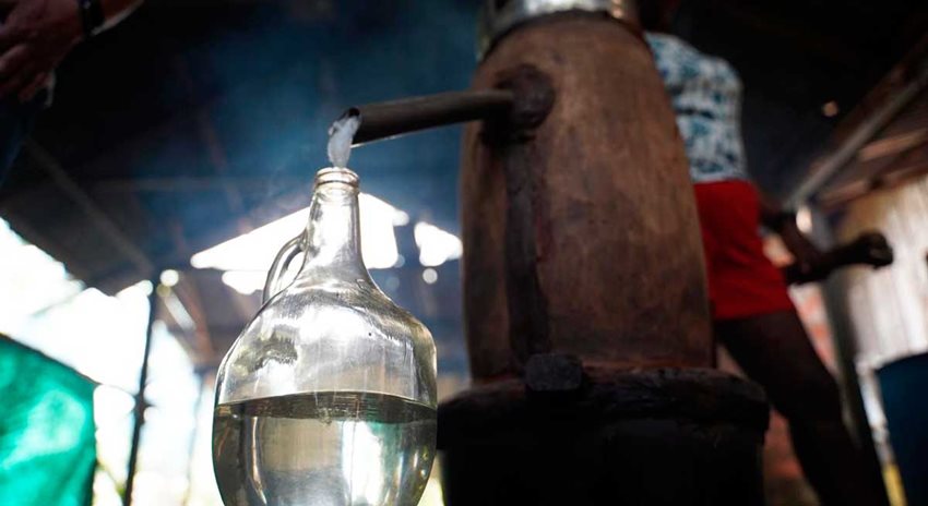 Viche vertiendo desde recipiente de madera a botella de vidrio.