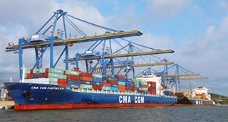 Barco blanco y azul, cargado con contenedores de colores.