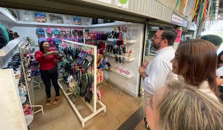 Dos mujeres y un hombre visitando el local de chanclas de una mujer.