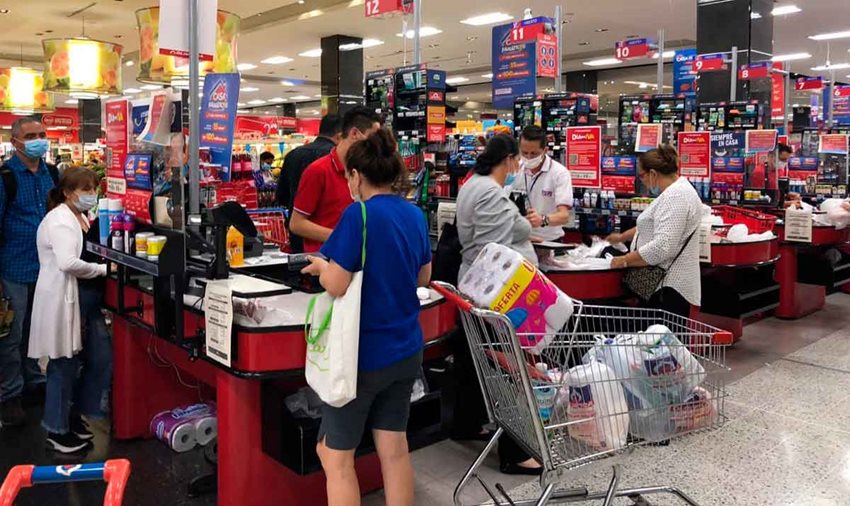 Personas en cajas de supermercado mayorista pagando los productos que seleccionaron.