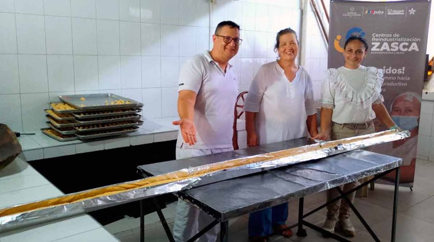 Un hombre y dos mujeres posando para la foto, junto a una gran achira, en medio de la fábrica.