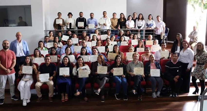 Hombres y mujeres, de pie y sentados, posando para la foto con su respectivo diploma.