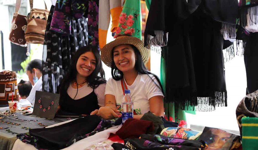 Dos mujeres posando para la foto en medio de su negocio de ropa y artesanías.