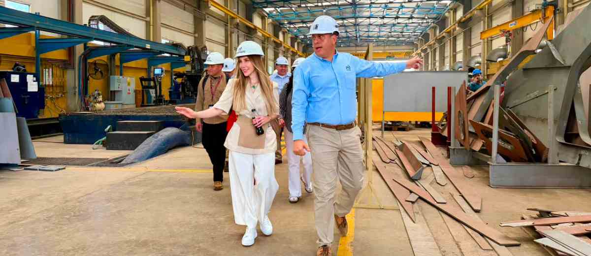 Descripción imagen: Ministra Diana Morales, con elementos de seguridad caminando, junto a un señor, por planta de industria naval.
