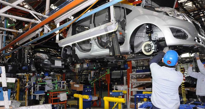 Dos hombres, en taller mecánico, arreglando un carro.
