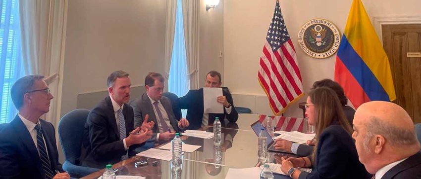 Hombres y mujeres, reunidos alrededor de una mesa, dialogando.