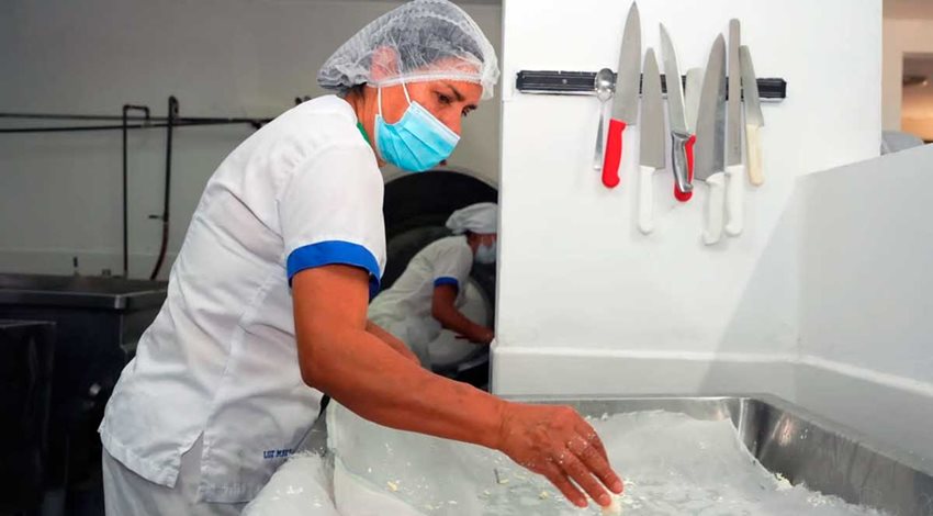 Mujer con elementos de bioseguridad, lavando instrumentos de cocina.