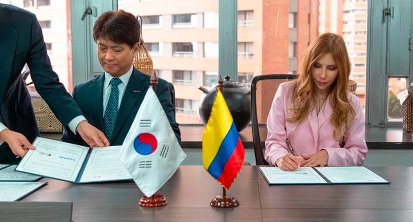 Hombre y mujer ejecutivos sentados en una mesa firmando documentos.