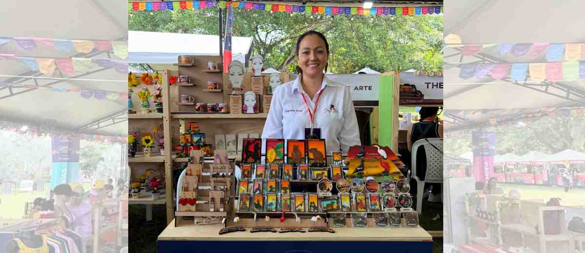 Descripción imagen: Mujer vendiendo productos en el estand, en medio de la feria.