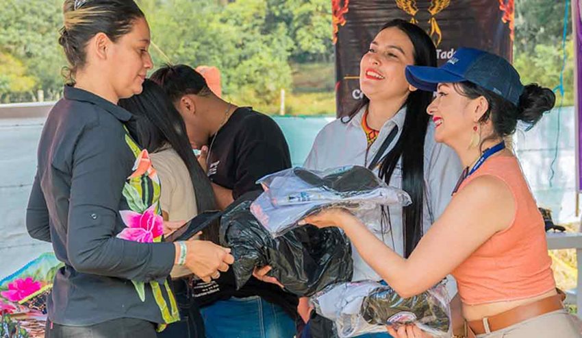 Dos mujeres entregando ropa a otra mujer vestida de negro.