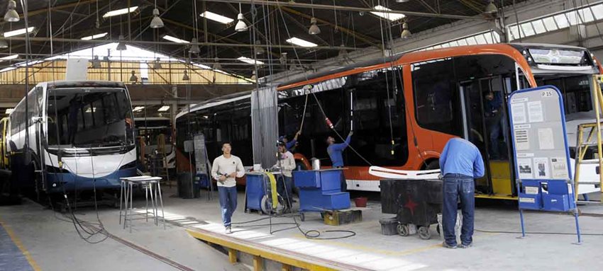 Hombres arreglando buses en un taller.