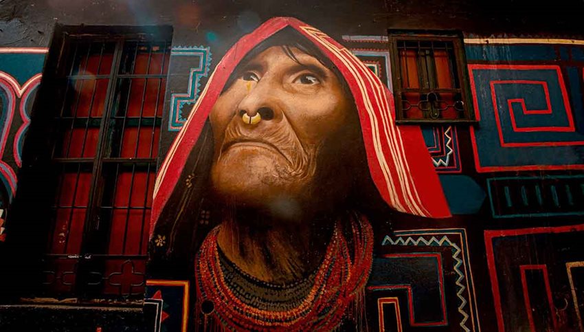 Pintura de una mujer indígena de la tercera edad, en la fachada de una casa.