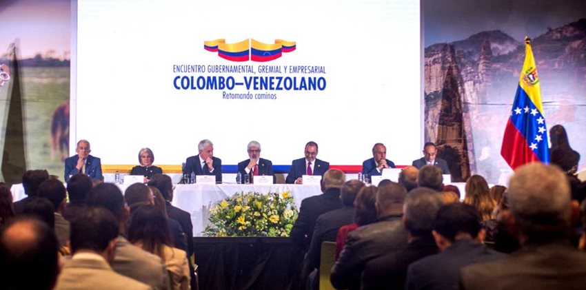 Funcionarios de Colombia y Venezuela sentados en una mesa hablándole al público.