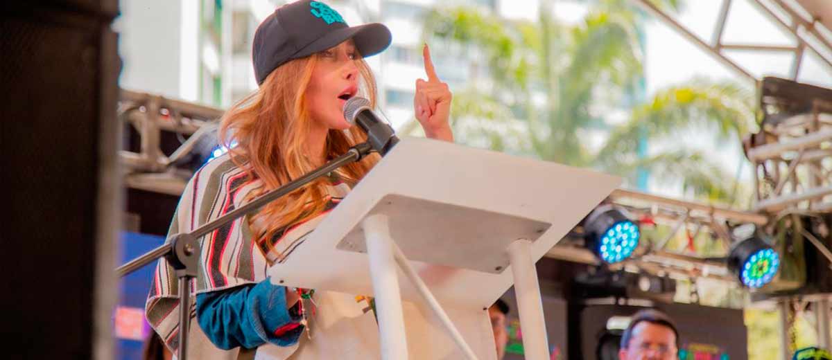 Descripción imagen: Ministra Diana Morales hablando por micrófono, en atril, desde el escenario.