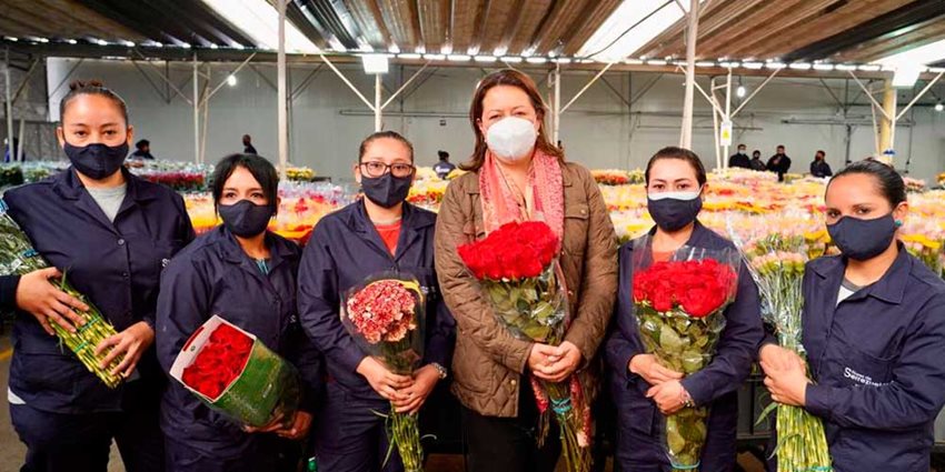 Ministra Ximena Lomaba junto a mujeres que trabajan en cultivos, sosteniendo rosas todas en sus manos.
