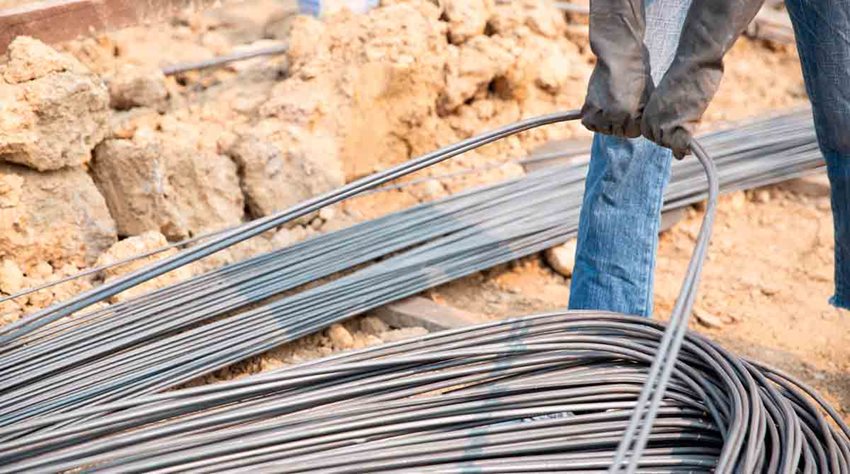Persona con guantes negros agarrando alambrón de acero.