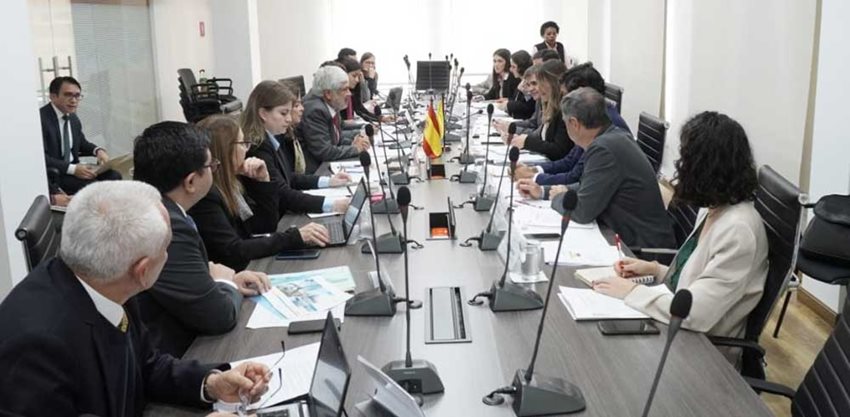 Funcionarios del Gobierno de Colombia y de España, reunidos en una mesa de juntas rectangular hablando.