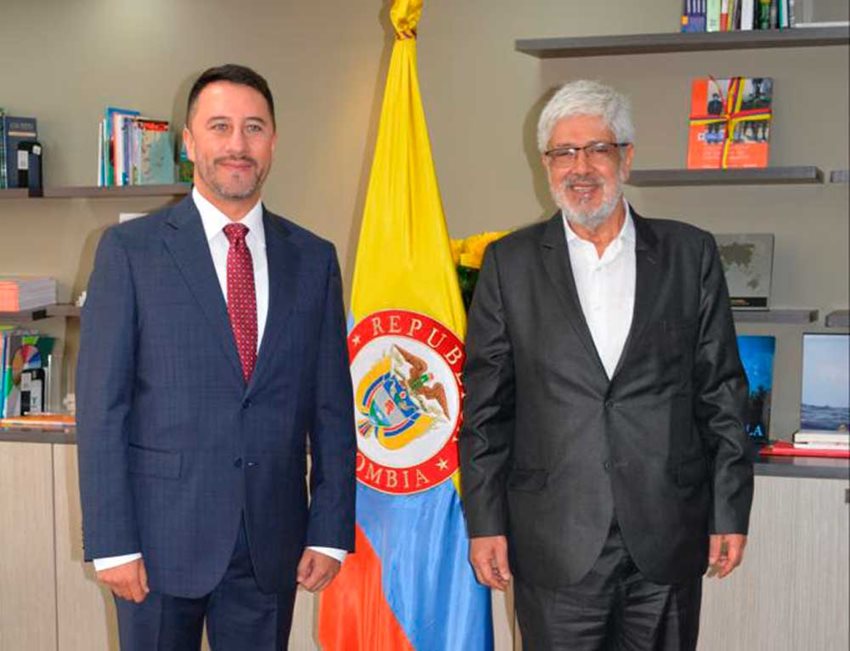 Arturo Bravo junto al ministro Germán Umaña, delante de la bandera de Colombia.