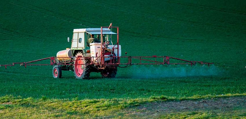 Tractor andando en medio del campo y regando agua.