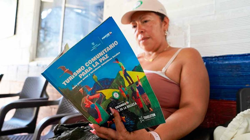 Mujer sentada en silla azul, leyendo un libro.