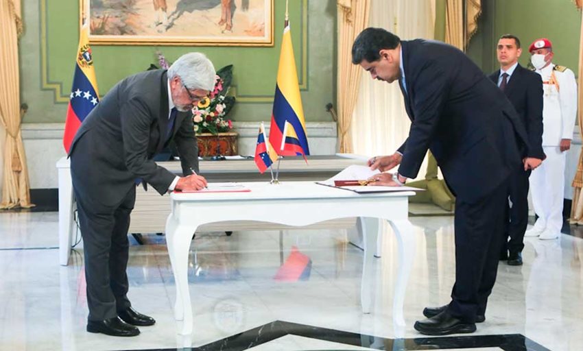 Ministro Germán Umaña y presidente de Venezuela, Nicolás Maduro, de pie firmando unos documentos en una mesa.