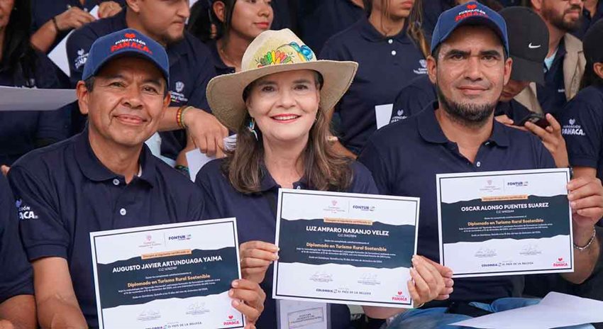 Descripción de la imagen: Dos hombres y una mujer, posando para la foto con camisetas azules oscuras y sus diplomas en las manos.