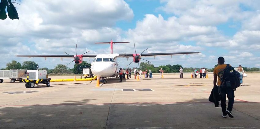 Personas caminando, en el día, para abordar un avión estacionado.
