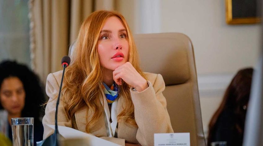 Ministra Diana Morales prestando atención a quien habla en medio de una reunión.