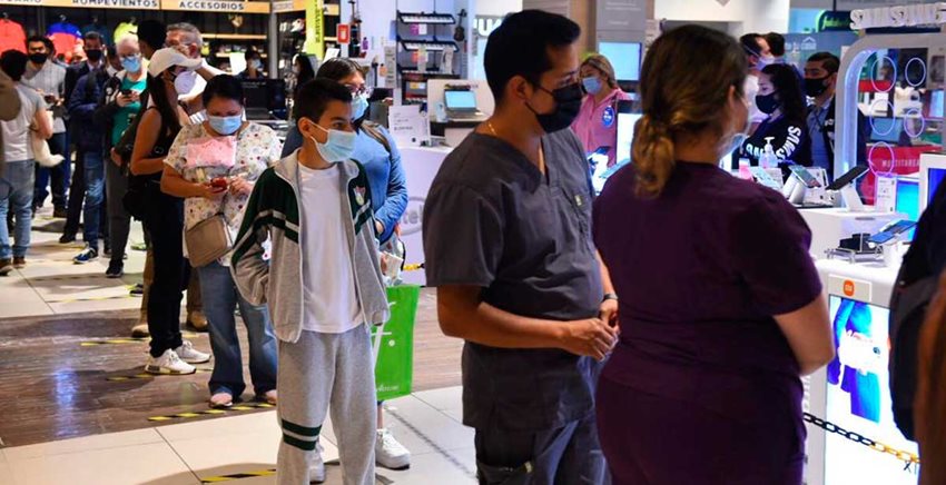 Personas haciendo fila en sección de tecnología en almacén de cadena.