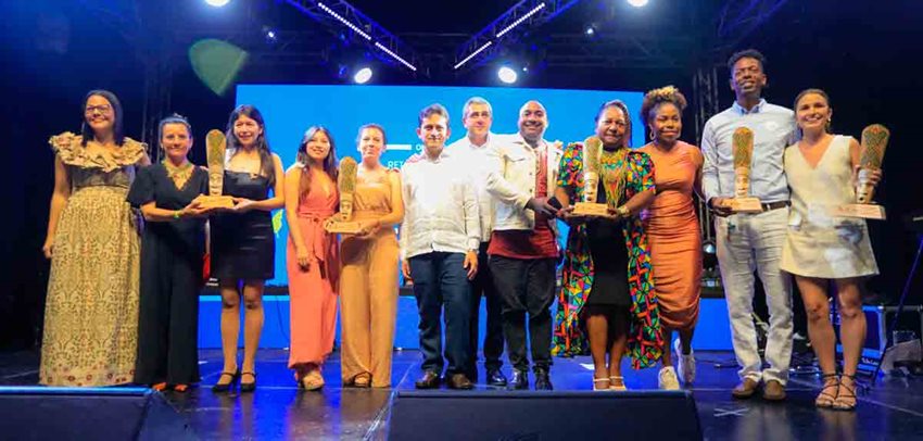 Descripción de la imagen: Ocho mujeres y cuatro hombres en el escenario, posando para la foto, con sus premios en las manos.