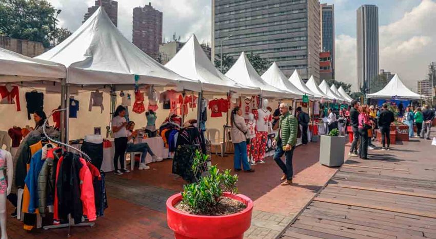 Carpas blancas con productos de emprendedores a la venta, en medio de una calle en Bogotá.