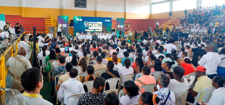 Personas sentadas en auditorio prestando atención a funcionarios del Gobierno hablando al frente.