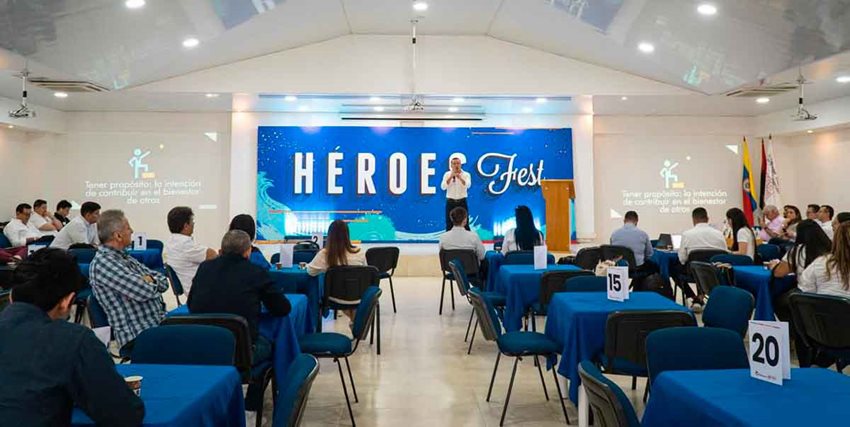 Personas prestando atención a hombre que está hablando al frente con micrófono.