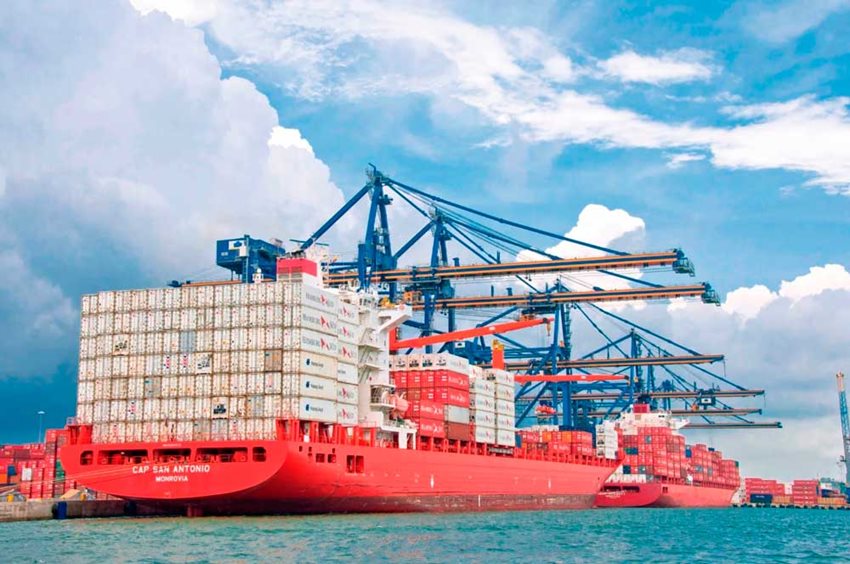 Barco rojo, en medio del mar, con contenedores a bordo para exportación.