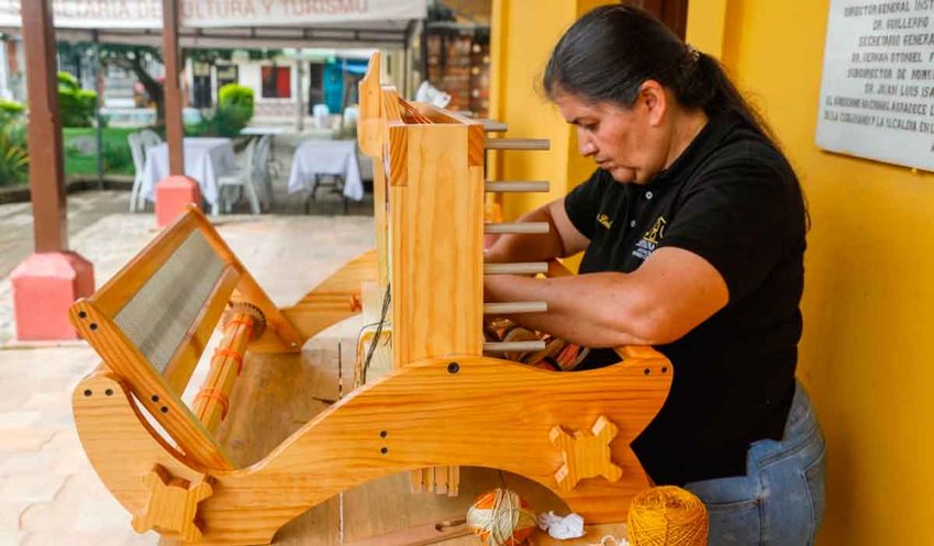 Mujer tejiendo en máquina de madera.