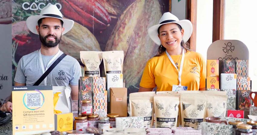 Hombre y mujer con sombreros vendiendo cacao en bolsas, en un estand.