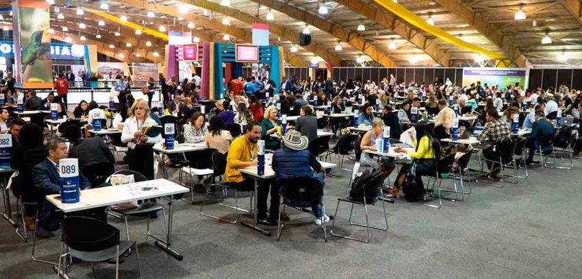 Personas reunidas en un gran salón, dialogando y haciendo negocios.