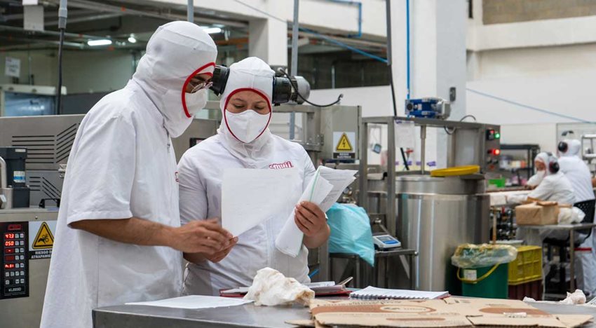 Hombre y mujer con trajes de seguridad blancos, dentro de un laboratorio.
