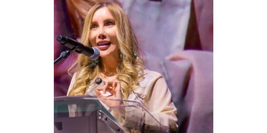 Descripción: Ministra Diana Morales hablando por micrófono, en atril, desde el escenario.