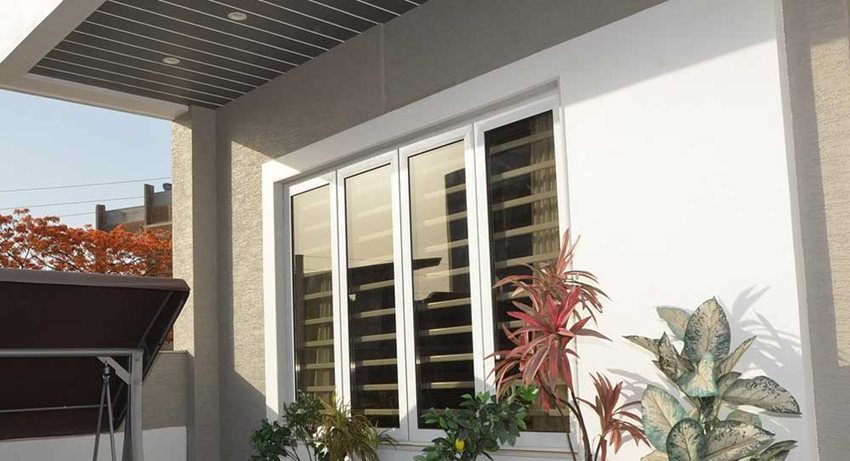 Imagen de la ventana de una casa, al lado se aprecian flores.