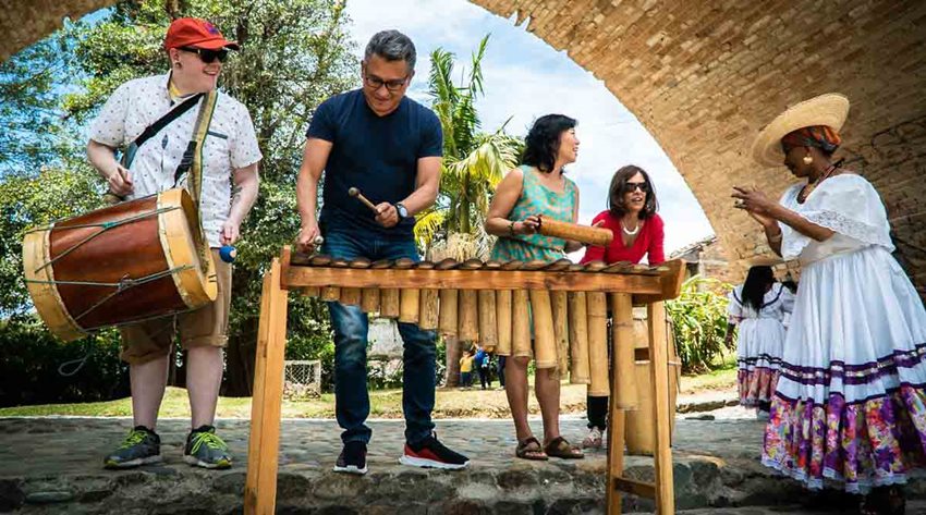 Descripción de la imagen: Turistas tocando instrumentos autóctonos de Colombia.