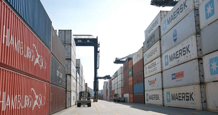 Contenedores de colores descargados en medio de la calle de un puerto.