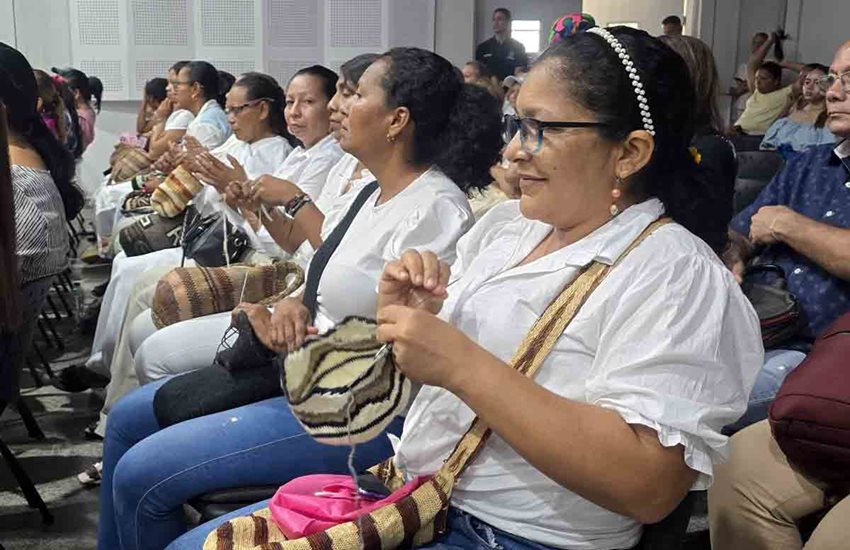 Mujeres sentadas, con mochilas y camisas blancas, prestando atención al frente.