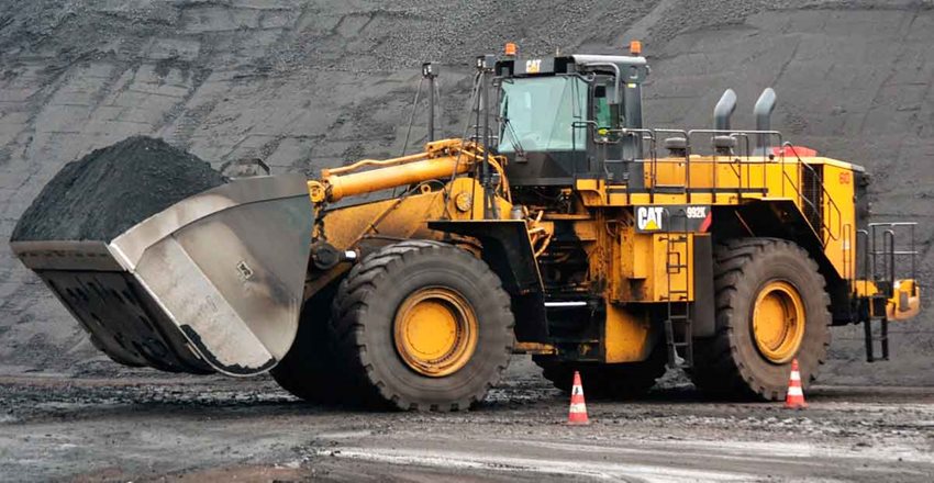 Máquina amarilla extrayendo carbón de una montaña.