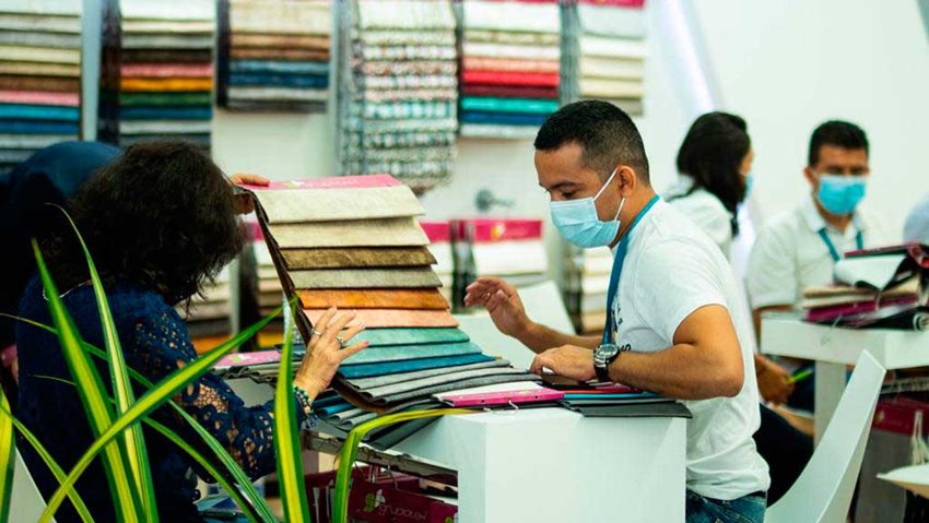 Mujer enseñándole un muestrario de telas a un hombre con tapabocas.